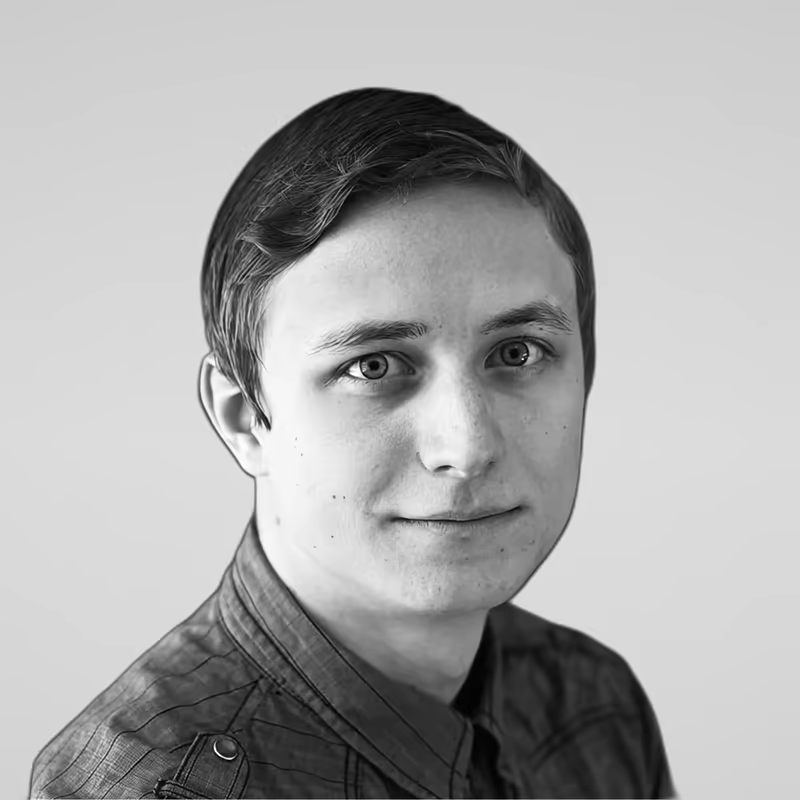 Black and white portrait of Alex Kurashev on a light gray studio background.