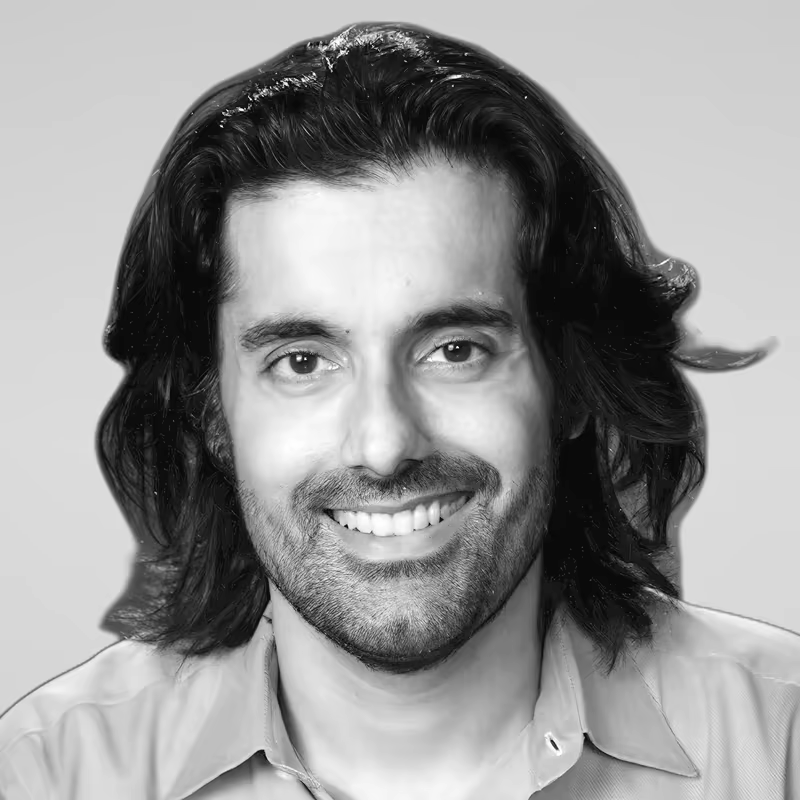 Black and white portrait of Husnain Bajwa on a light gray studio background.