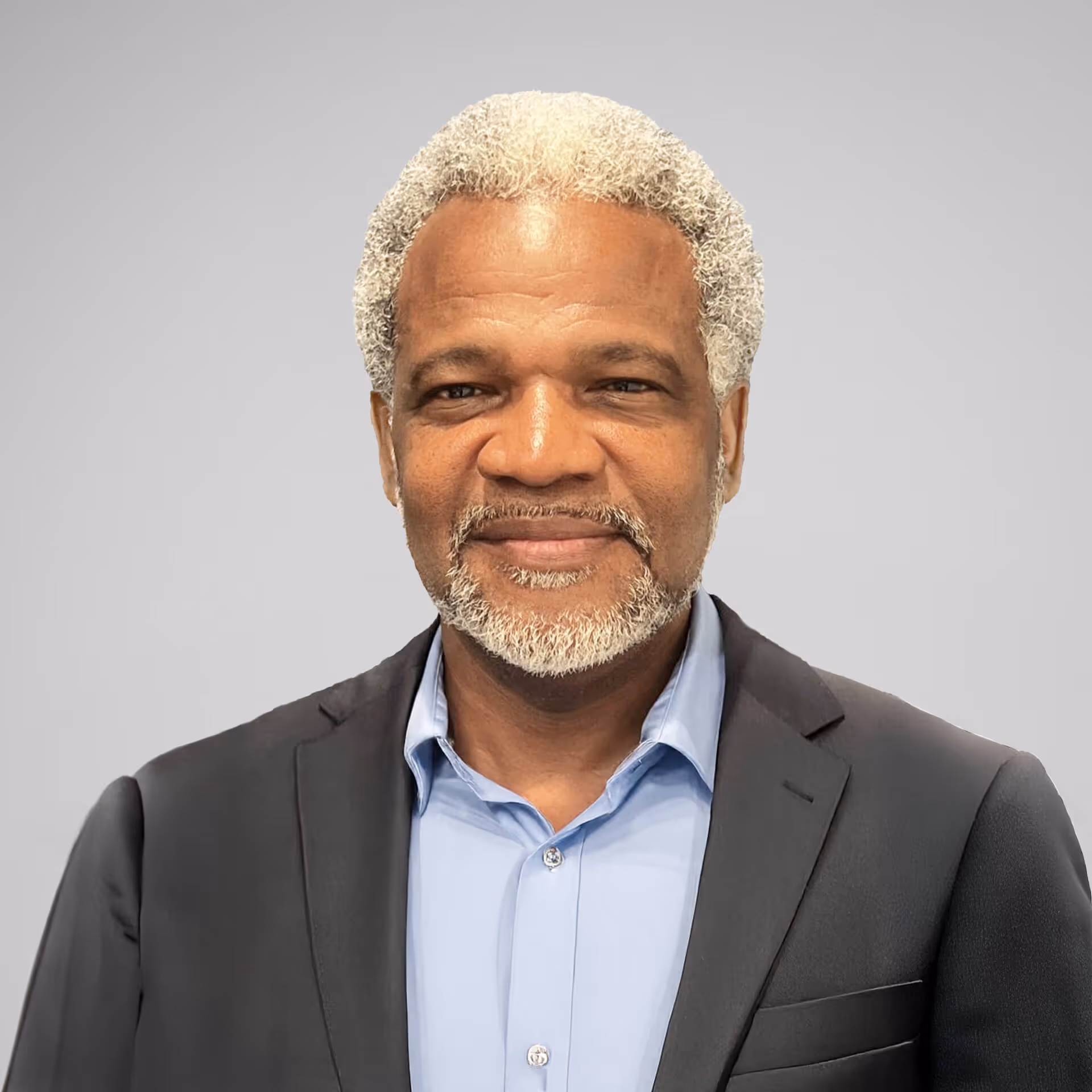 a portrait of a black man with white hair, slightly smiling, wearing a blazer and a blue shirt