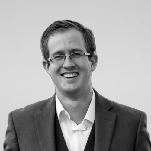 Black and white portrait of Kevin Farrow on a light gray studio background.