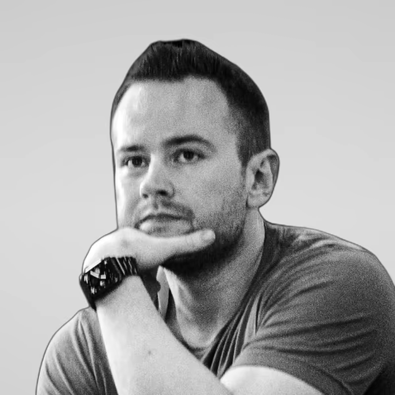 Black and white portrait of Maik Robert on a light gray studio background.