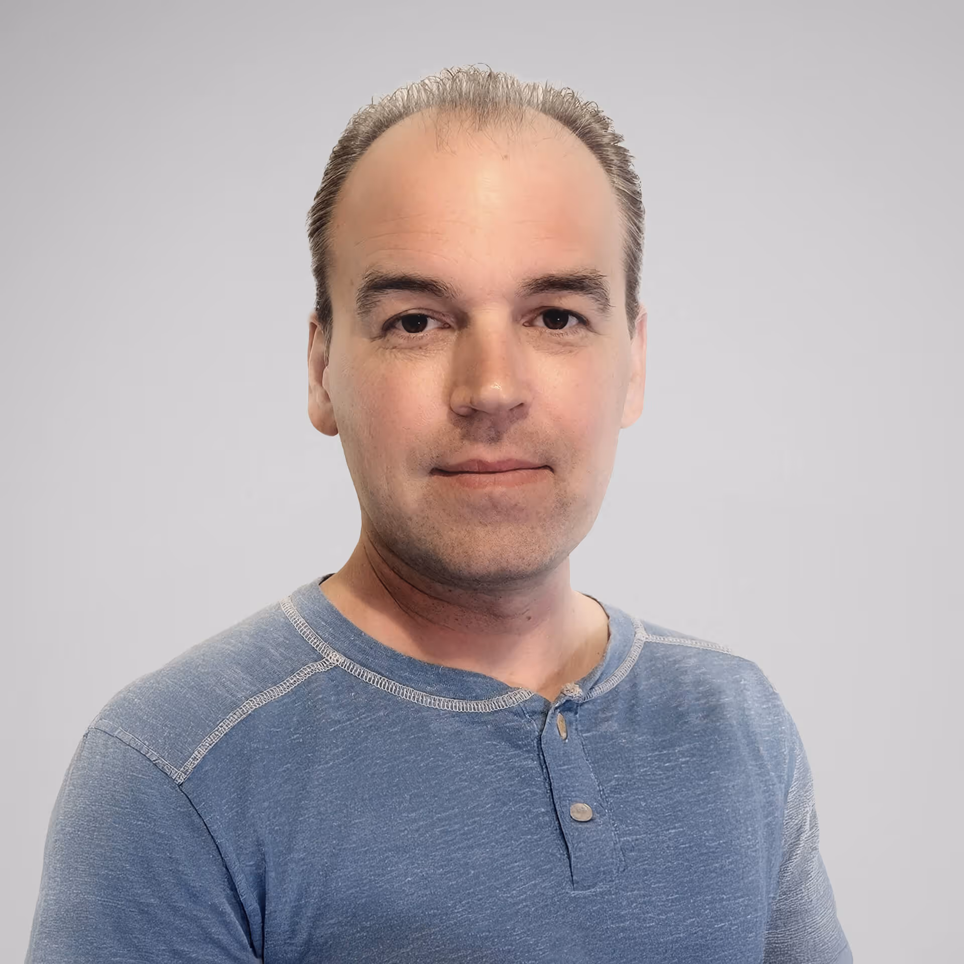 a portrait of man wearing a blue long sleeve, looking directly into the camera